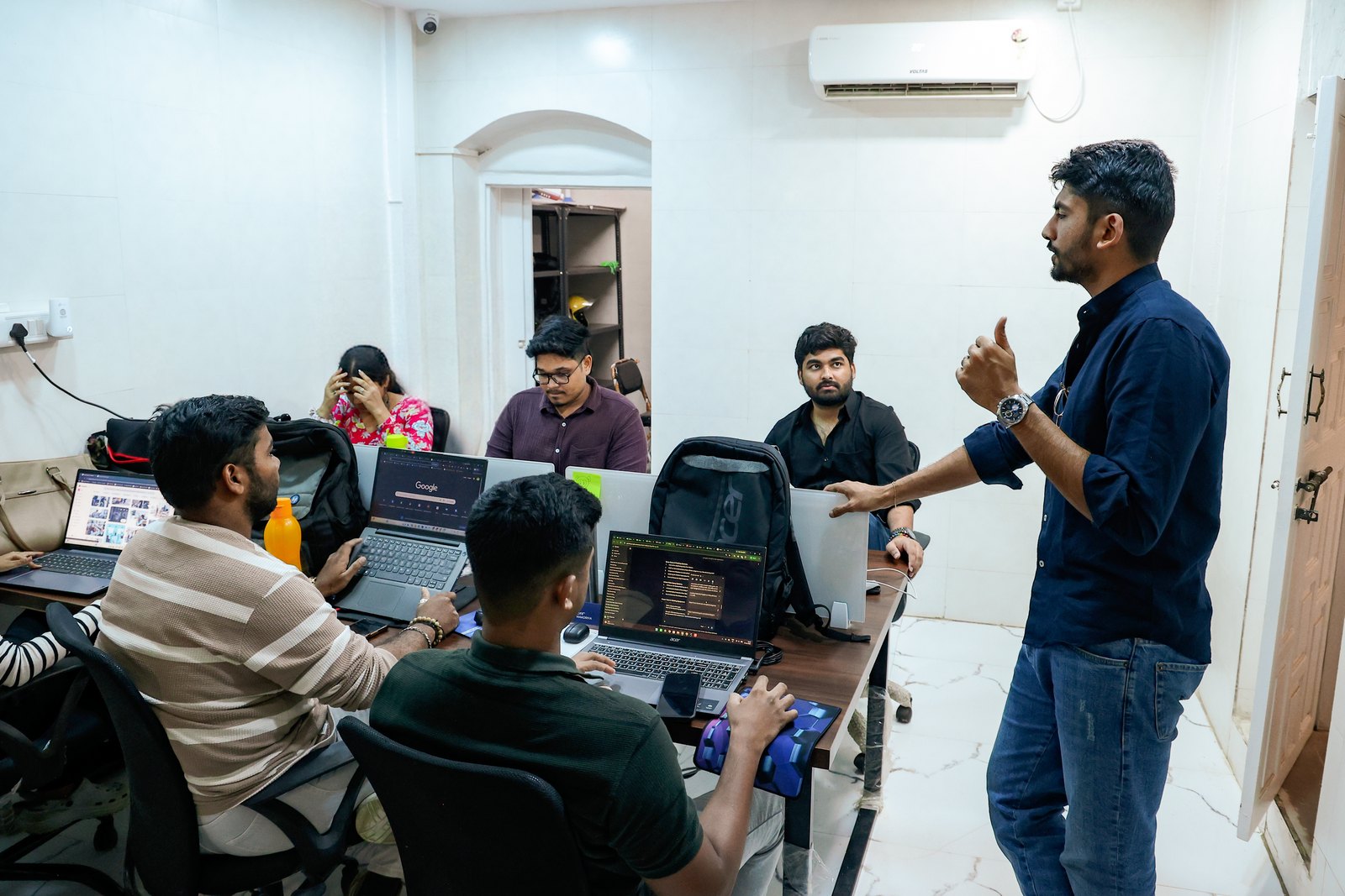 Manan Mehta running a stand-up with the team around their laptops